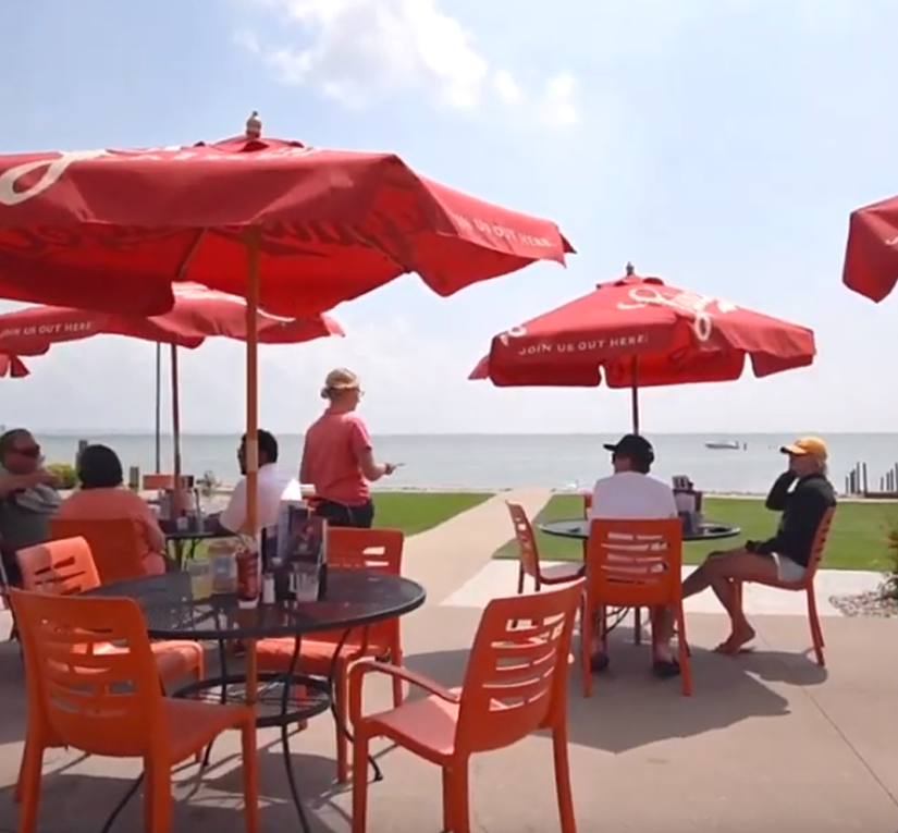 People sitting at outside tables on the shore of Lake Winnebago