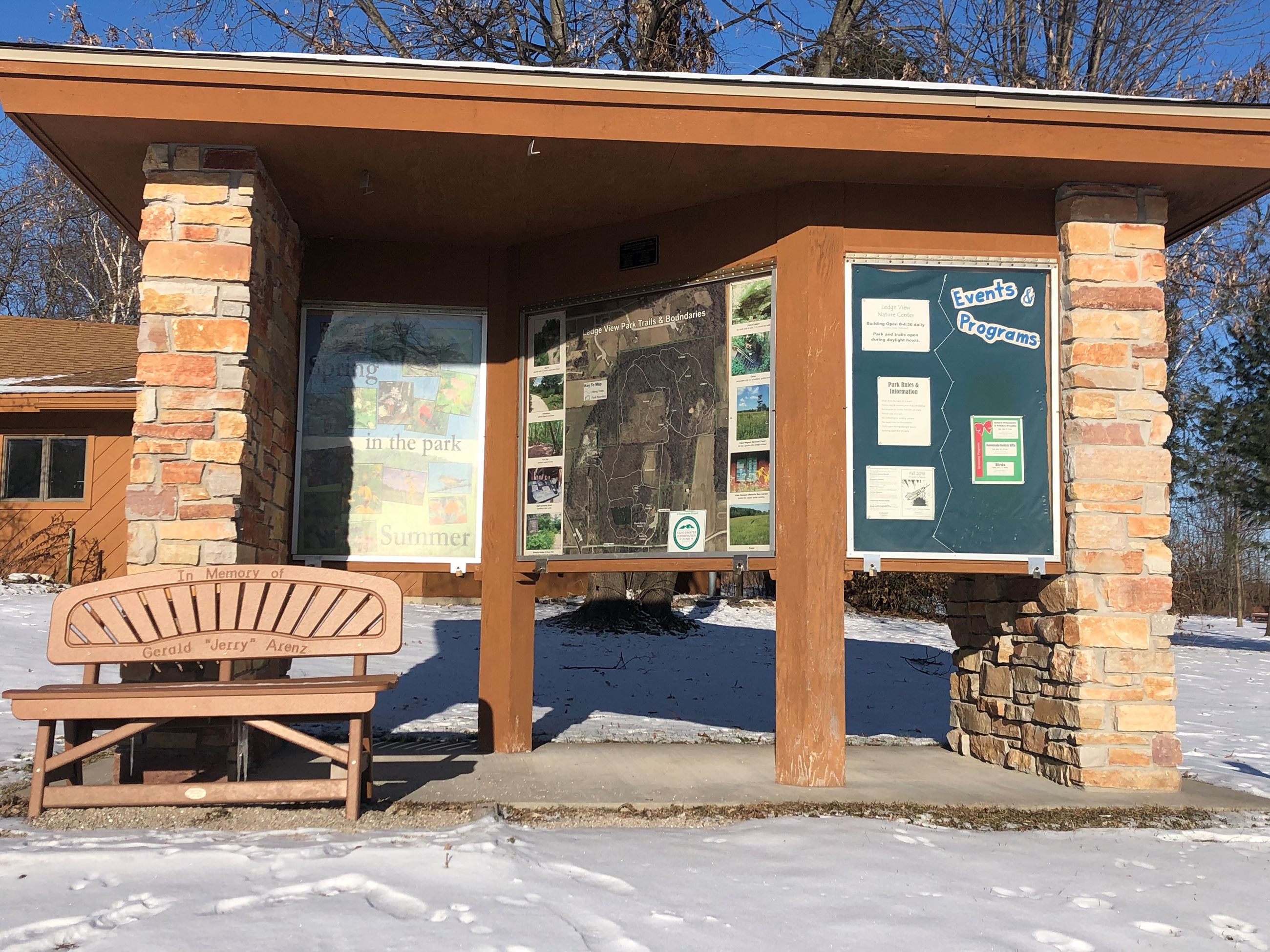 A stone and wood kiosk with information on it for park visitors.